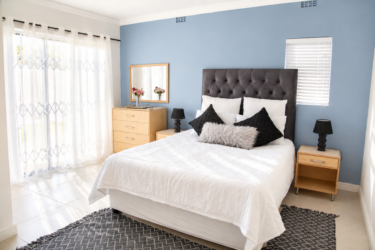 Bedroom with queen-size bed, velvet headboard and dusty-blue feature wall