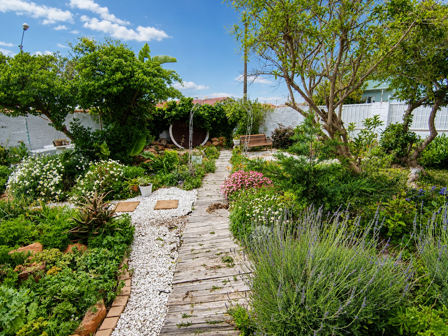 Tranquil cottage garden with flowers, wooden walkway and seating