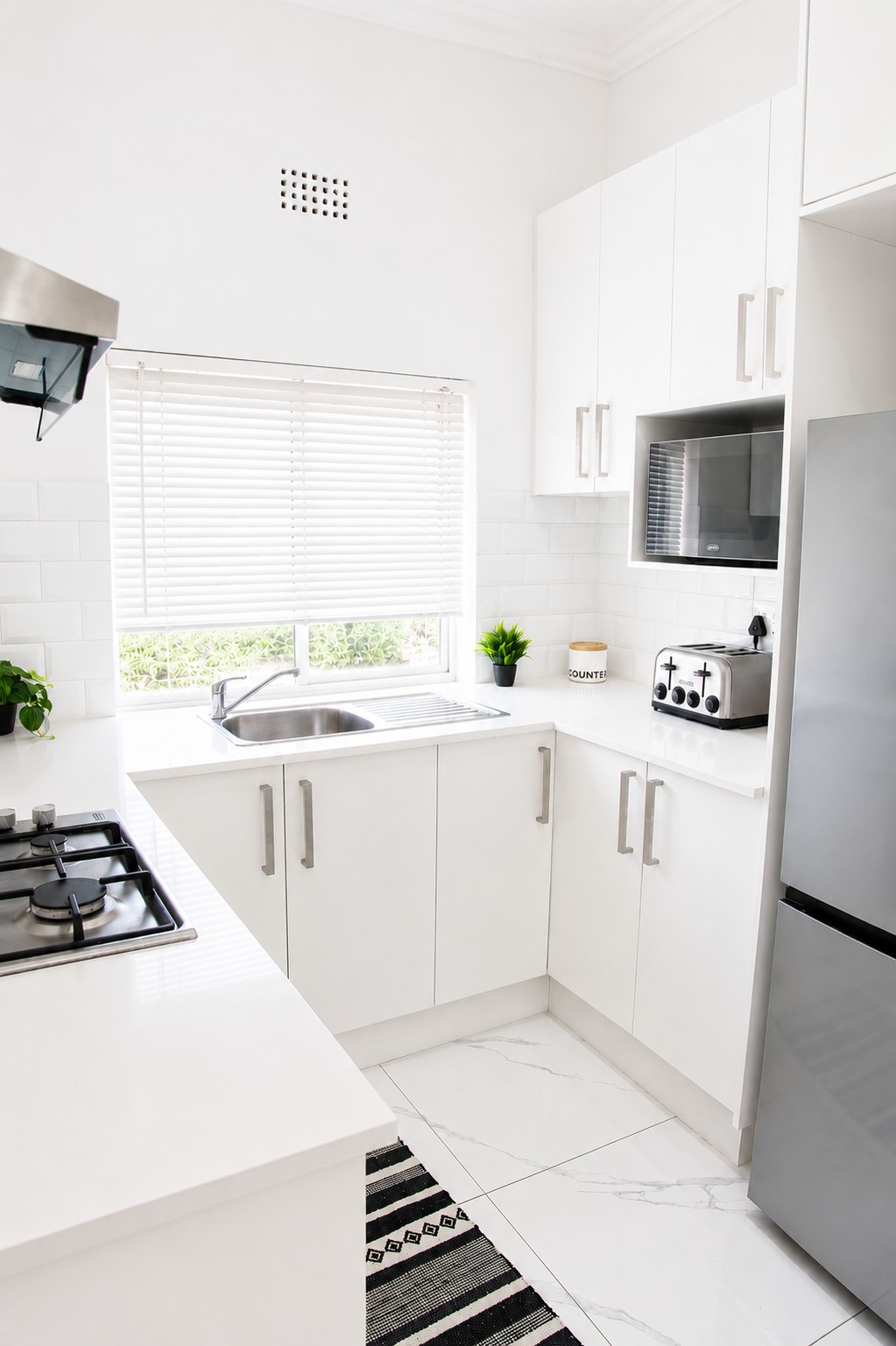 Modern white self-catering kitchen with gas hob, oven and full appliances